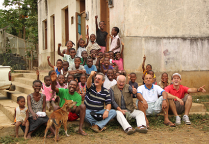 Andre-derberd-et-son-fils-levent-le-bras-avec-plein-enfants-devant-ecole