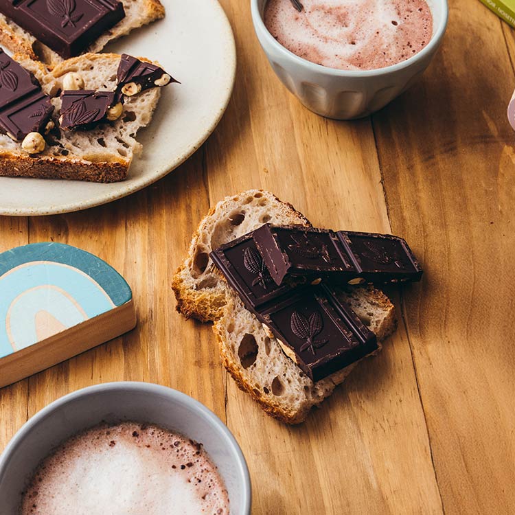 Carrés de chocolat noir aux amandes entières bio et équitable de la marque Kaoka sur une tranche de pain de campagne