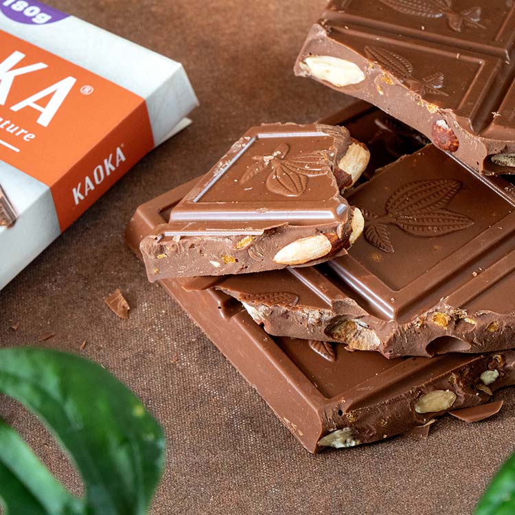Pile d'épais carreaux de chocolat au lait gourmand aux amandes entières, caramel et à la fleur de sel bio et équitable de la marque Kaoka