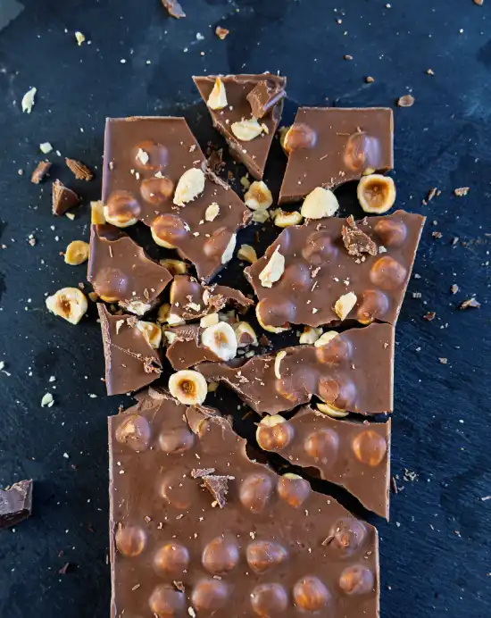 Vue de dessus d'une tablette de chocolat au lait gourmande aux noisettes entières cassée