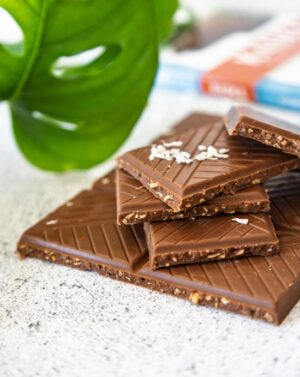 Pile de carrés de chocolat au lait aux brisures de noix de coco toastées de la marque Kaoka|Pile de carrés de chocolat au lait aux brisures de noix de coco toastées de la marque Kaoka