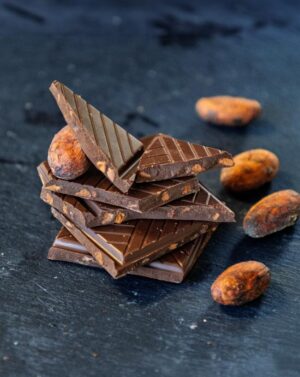 Pile de carrés de chocolat aux éclats de fèves de cacao caramélisés avec des fèves de cacao sur une ardoise