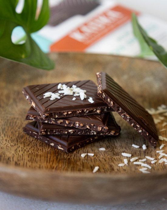Pile de carrés de chocolat aux brisures de noix de coco dans une assiette en bois