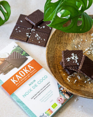 Tablette de la marque Kaoka avec des carreaux de chocolat à la noix de coco dans une assiette en bois