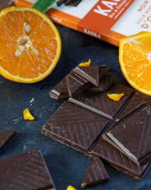 Photo d'une tablette de chocolat avec des oranges entières sur une ardoise