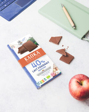 Une tablette de chocolat au lait 40% cacao fondante Kaoka et des carrés de chocolat au lait sur un bureau