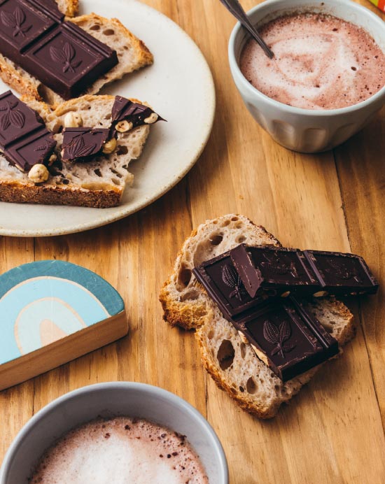 Tartine de pain avec du chocolat noir aux amandes entières accompagné d'un chocolat chaud et de jouets pour enfants